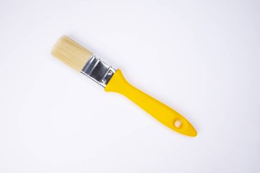 Beyaz arka planda sarı saplı temiz boya fırçası. Küçük inşaat fırçası