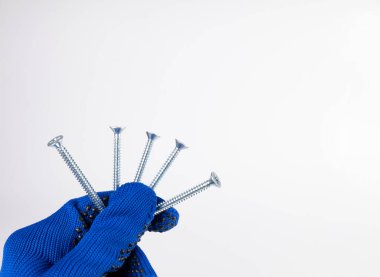 Beyaz arka planda kendi kendine dokunan vidalar. Bir el, beyaz arka planda bir sürü kendini beceren vida tutar..