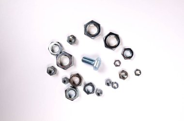 Cıvata fındıklar arasında beyaz bir zeminde yatıyor. Seçim sorunu. Sorun doğru boyutu bulmakta. Seks partneri seçerken ki sorunun metaforu.