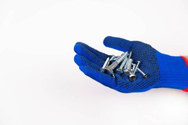 İnşaat malzemeleri. Mavi eldivenli bir el beyaz arka planda kendi kendine dokunan vidalar tutar. Tamir için kendi kendine dokunan vidalar. Beyaz arka planda kendi kendine dokunan vidalar