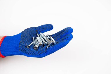 İnşaat malzemeleri. Beyaz arka planda kendi kendine dokunan vidalar. Eldivendeki bir el kendi kendine dokunan vidaları tutar. Beyaz arkaplanda kendi kendine dokunan vidalar