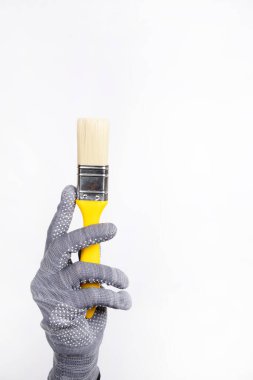 İnşaat malzemeleri. Beyaz arka planda küçük bir boya fırçası. Bir kadının eli boya fırçasını tutar.
