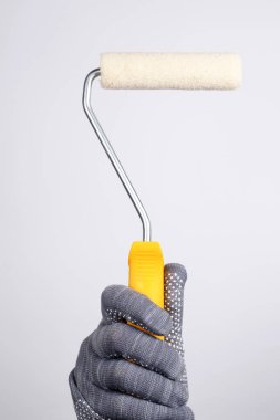 Beyaz arka planda boya silindiri. Beyaz arka planda bir boya silindiri tutuyor. Duvarları boya rulosuyla boyayın.