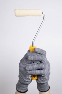 Beyaz arka planda boya silindiri. Beyaz arka planda bir boya silindiri tutuyor. Duvarları boya rulosuyla boyayın.