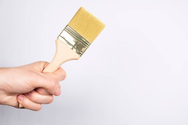 Beyaz arka planda büyük, temiz boya fırçası. Erkek eli fırça tutuşu