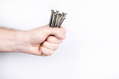 Beyaz arka planda kendini beceren bir sürü vida var. Bir adamın eli kendini beceren vidaları tutar.