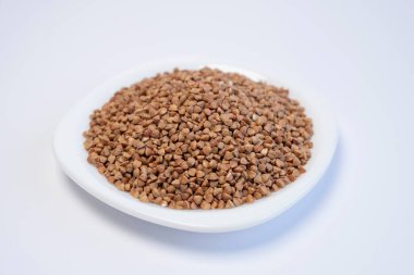 Beyaz arka planda beyaz bir tabakta karabuğday. Sağlıklı yiyecekler. Gevrekler