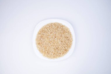 Pirinç. Beyaz arka planda beyaz bir tabakta pirinç, üst manzara. Yemek için pirinç seçimi. Suşi için pirinç seçiyorum. Sağlıklı taneler. Sağlıklı yemek..