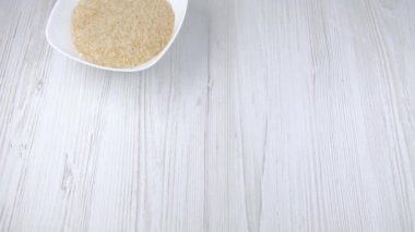 Kadının eli masaya bir tabak pirinç koyar. Tabakta pilav. Sağlıklı yiyecekler. Yemek malzemeleri.