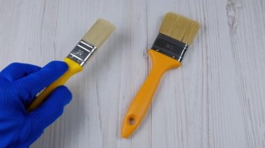 El fırçaları tutar. Parmak fırçayı gösteriyor. Onarım aracı seçimi
