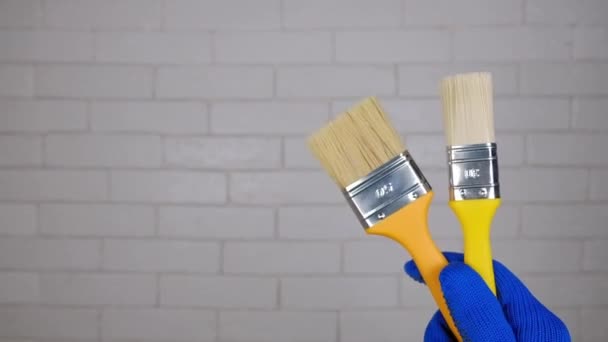 手拿着刷子一只戴着手套的手把刷子放在墙的后面 刷一下墙 自由的文字空间 建筑材料广告 — 图库视频影像