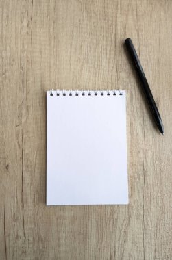 Tahta masadaki kareli not defterini ve siyah kalemi aç, yakın plan