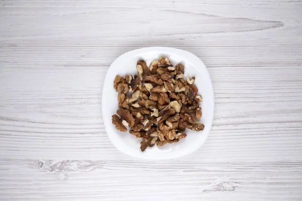 Beyaz tabakta ceviz. Masada bir tabak fındık var. Sağlıklı yiyecekler. İnsan sağlığı..