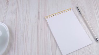 Evdeki işyerinde. Kalem, defter, masaya kahve. Ofiste kahve var.