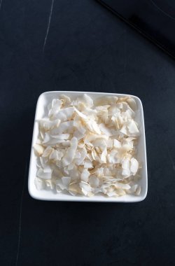 Siyah masa üstünde hindistan cevizi taneli beyaz tabak, üst manzara. Sağlıklı yiyecekler. sürdürülebilir gıda