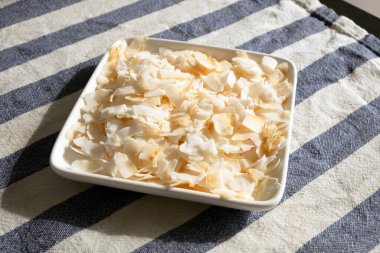 Siyah arka planda çizgili havluyla beyaz tabakta hindistan cevizi taneleri. Sağlıklı yiyecekler. vejetaryen yemeği