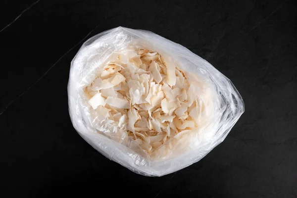 Hindistan cevizi. Siyah bir masanın üzerindeki bir torbada hindistan cevizi taneleri. Sağlıklı yiyecekler. Günlük yaşamda plastik poşet kullanımı. Ekoloji sorunu.