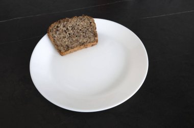 Siyah bir masada beyaz bir tabakta ekmek. Öğle yemeği için ekmek. Ekmek yemeye.