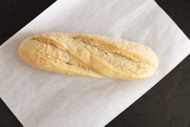 Beyaz parşömen üzerinde taze pişmiş ekmek, üst manzara. Ekmek masada.