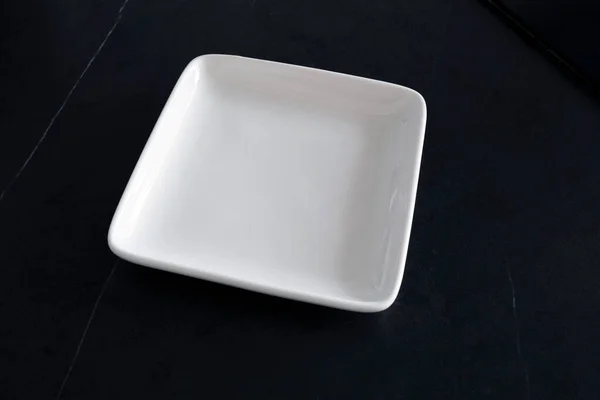Άδειο Λευκό Τετράγωνο Πιάτο Στο Μαύρο Τραπέζι — Φωτογραφία Αρχείου