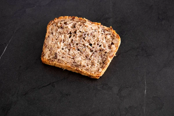 黑桌上的谷物面包 — 图库照片