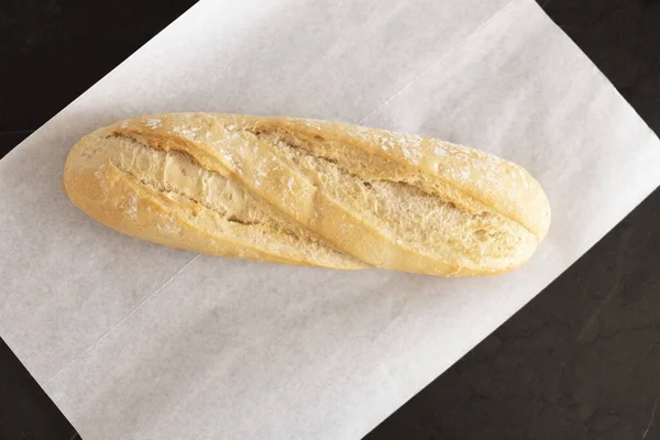 Beyaz parşömen üzerinde taze pişmiş ekmek, üst manzara. Ekmek masada.