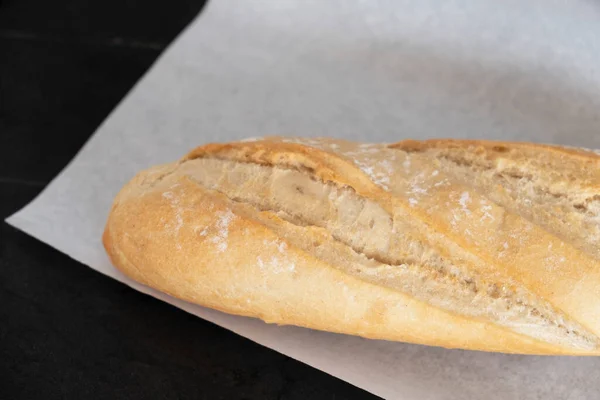 Biały Chleb Pergaminie Czarnym Stole Świeżo Upieczony Chleb — Zdjęcie stockowe