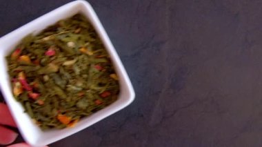 Çerçevede beyaz tabakta katkı maddeleri olan yeşil çay görünür, yakın plan.