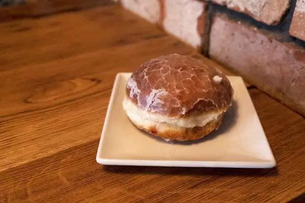 Tahta bir masada, beyaz bir tabakta kızarmış çörek. Lezzetli hamur işleri. Yağlı yemek.