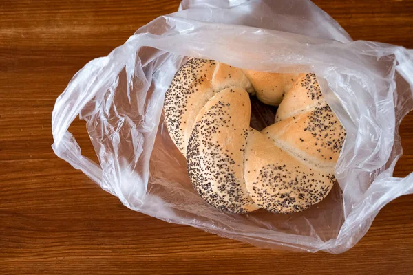 Bake. Roll with poppy seeds in a plastic bag on a wooden table top view