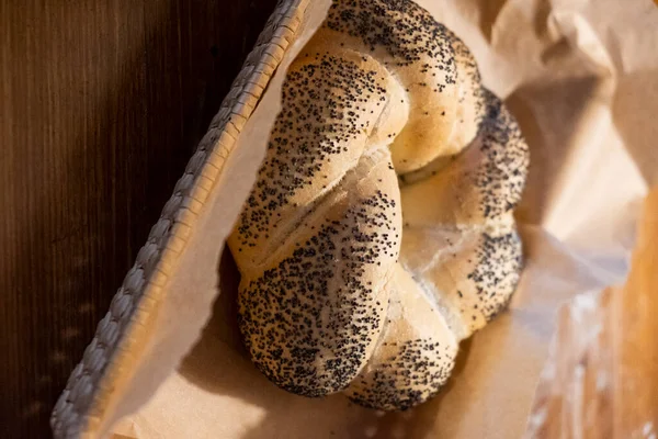 Bun in a basket on parchment. The basket is on a wooden table. Bun. Fresh bakery