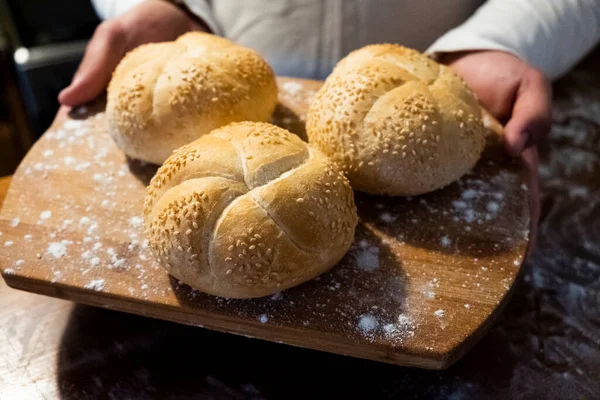 man board with buns with sesame. Flour is scattered on the table. The man made buns. Buns for breakfast. Bakery products
