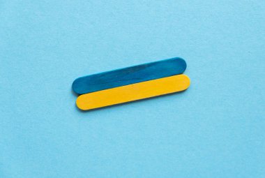 flag of ukraine from wooden sticks on a blue background close-up
