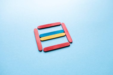 Flag of Ukraine in a red square side view. War in Ukraine. Anxiety. Danger. Wooden sticks on a blue background