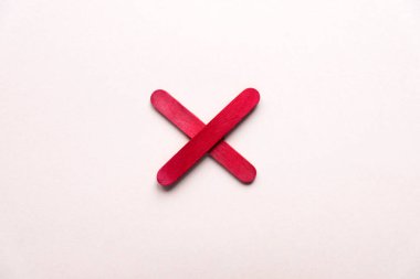 red cross made of wood on a beige background. prohibition sign