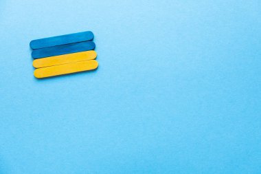 Blue and yellow wooden sticks. Flag of Ukraine on a blue background, free space