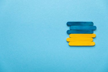Blue and yellow wooden sticks. Flag of Ukraine on a blue background, free space