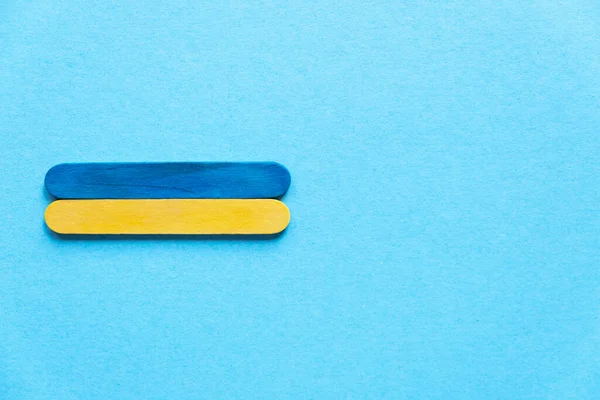 Ukrainian flag top view. Ukraine flag on a blue background, space for text. wooden sticks in the colors of the flag of ukraine on a blue background, top view. Ukraine's Independence Day. Wooden sticks. 