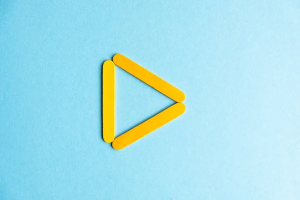 The play sign is yellow on a blue background. Inverted treulnik on a blue background. Geometric stick figure