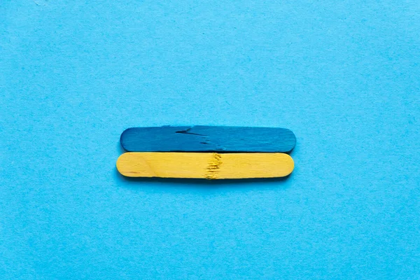 Flag of ukraine from wooden sticks on a blue background. War in Ukraine. The wooden sticks are broken. Symbol of war and suffering