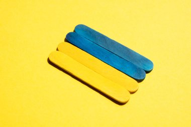 Flag of ukraine from wooden sticks on a yellow background