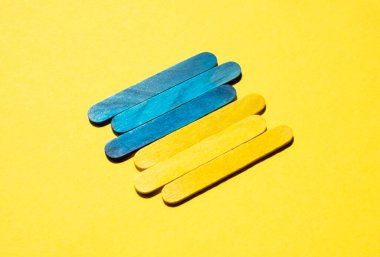 Ukrainian flag from colored sticks on a yellow background, side view