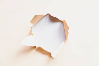 hole in beige paper on a gray background, space for text