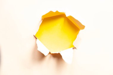 hole in beige paper on yellow background, space for text