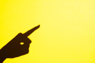 the shadow of a female hand points with a finger to the free space. Place for text