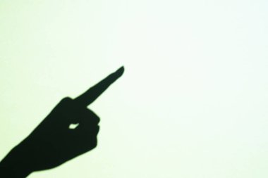 the shadow of a female hand points with a finger to the free space. Place for text