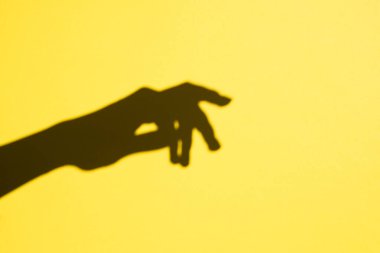 shadow female hand on a yellow background, free space