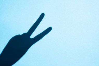 shadow gesture victory on blue background, free space