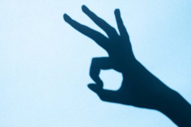 shadow gesture ok on blue background, free space