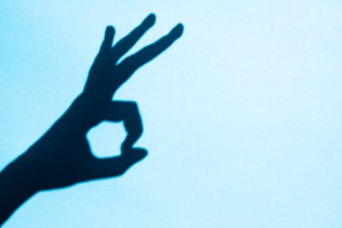 shadow gesture ok on blue background, free space